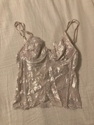 vintage skimrande lace topp - fin benvit korsettliknande lace topp med bygel både under kuporna och på sidorna. kuporna har vikt sig på nåt konstigt sätt, men det rätar ut sig när man väl har den på sig. kan nog fixas om man vill. står s på lappen men den känns definitivt mer som en xs.