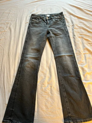 Bootcut jeans från Gina Tricot grå - Säljer ett par grå bootcut jeans från Gina Tricot i storlek 164. Jeansen har klassisk femficksdesign, knappgylf och är tillverkade i mjuk bomullsdenim med lätt utsvängda ben. Perfekta för dig som gillar en retroinspirerad look.