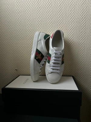 Gucci Ace Skor  - Ett par snygga Gucci Ace skor i väldigt bra skick!Storlek 42 men kan även passa 43🙌 Box och Dustbag ingår | Skriv vid mera bilder/frågor.         Perfekt för dig som vill ha exklusiva skor inför våren.                                                                          Ny pris 9 250kr!!!                                              Fraktar inom 24 timmar 🚚. 