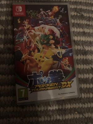 Pokkén Tournament DX till Switch - Säljer spelet Pokkén Tournament DX till Nintendo Switch. Omslaget har färgstarka Pokémon som Pikachu och Charizard i en actionfylld design. Perfekt för dig som gillar fighting och Pokémon. Spelet kommer i original plastfodral.
