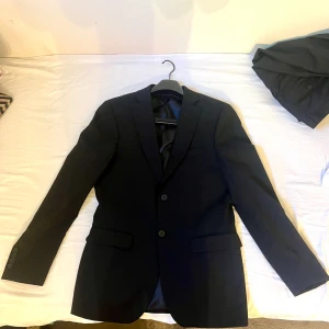 Kostym från Dressmann - Storlek på Kavajen är 46L och kostymbyxorna är storleken 30/32. Den är bara använd en gång så den är som ny. Färg svart. Kan diskuteras om pris