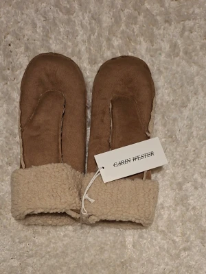 Bruna vantar från Carin Wester - Mysiga bruna tumvantar från Carin Wester i mjukt beige, fluffigt foder och som är uppvikt vid handlederna, perfekt när det är kallt😊❄️
