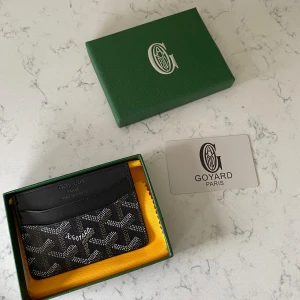 Svart kortfodral från Gy - Exklusivt svart kortfodral från Gy med ikoniskt mönster i vitt och grått. Tillverkat i skinn med flera kortfack och klassisk Gy-logga framtill. Kommer i originalask och med certifikat.