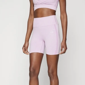 Ljusrosa seamless träningsshorts från ICANIWILL - Säljer ett par ljuslila seamless träningsshorts från ICANIWILL. De är högmidjade med ribbad midja och har diskreta ränder längs sidorna. Materialet är stretchigt och passar perfekt för gym eller annan träning. Logga broderad framtill.