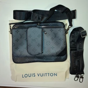 Louis Vuitton Väska - Svart och grå louis vuitton tripple messenger bag. Ny skick. Det finns 2 band så man kan ändra vilken sida man vill ha den lilla väskan på. Mitt pris: 1000kr 