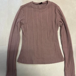 Ribbad brun långärmad tröja - Säljer en ribbad brun/rosa långärmad tröja med rund hals.Materialet känns mjukt och stretchigt.
