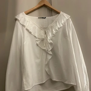 Vit blus med volang och knyt från 157 - Supersöt vit blus från 157 med volangdetaljer. Den är helt ny aldrig använd , har dock tyvärr tagit bort prislappen , ja säljer den för att ja köpte fel storlek 