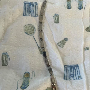 Silverfärgat länkarmband i metall - Säljer ett stilrent armband i silverfärgad metall med rektangulära länkar. Vissa länkar är blanka medan andra har ett diskret mönster som ger en cool kontrast. Perfekt accessoar för dig som gillar minimalistisk och modern stil.