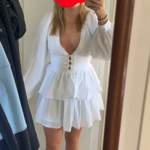 Studentklänning från showpo  - Supersöt vit kortklänning med v-ringad front, långa puffärmar och knappar framtill. Passar både XS-S. Klänning har en defekt på ena armen, de sista bilden, men de är inget som påverkar helhetsintrycket. Perfekt till student eller sommaren.