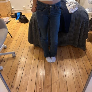 Blå bootcut jeans från Gina Tricot - Snygga blå jeans från Gina Tricot i klassisk bootcut-modell. Jeansen har normal passform, fem fickor och gylf med knapp och dragkedja. Tillverkade i jeansmaterial med snygga kontrastsömmar. Perfekta för dig som gillar en tidlös look.