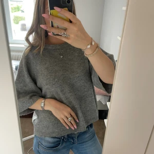 Grå stickad tröja  - Mysig grå stickad tröja från 157 med avslappnad passform och trekvartsärmar. Perfekt för lager-på-lager och enkel att styla med jeans eller kjol. Ribbstickade detaljer vid halsringning och nederkant ger en snygg finish.