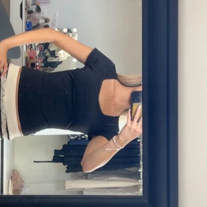 Svart topp - En svart, tight topp med korta ärmar och snygg fyrkantig ringning. Toppens passform är figurnära och den har en enkel, stilren look som passar till många olika outfits. Den har brodering upptill, vet ej vart den är ifrån men på lappen står det ”stories” 💗
