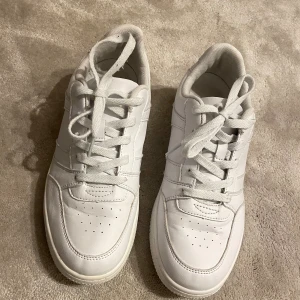 Vita sneakers i skinn - Snygga helvita sneakers med klassisk design och rund tå. Skorna har snörning framtill, perforerade detaljer på tån och en platt sula. Tillverkade i skinn och passar perfekt till streetwear eller casual outfits. Hör av dig vid frågor😁
