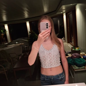 Vit spetsig linnetopp från H&M XS - Supersöt vit linnetopp från H&M i storlek XS. Toppen är croppad med justerbara smala axelband och har ett blommigt spetsmönster över hela framsidan. V-ringad med fina virkade detaljer längs kanten. Jag är 172 så den är inte lika kort. Nypris 200kr