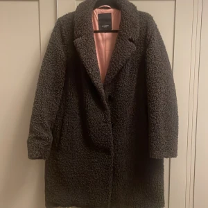 Brun teddyjacka från Rockandblue - Mysig brun teddyjacka från Rockandblue med rosa satinliknande foder. Jackan har klassisk krage, knäppning framtill och lång ärm. Perfekt för dig som vill ha en varm och trendig look under kyliga dagar. Knappt använd riktigt bra skick