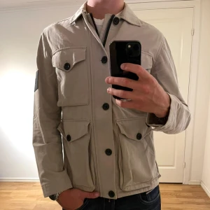 Beige Fieldjacka Peak Performance  - Fieldjackan - Peak Performance. Färgen är beige och storleken är Sz Den har inga defekter och skicket är utomordentligt. Sjukt najs passform och passar perfekt till hösten Tveka inte på att höra av er dig vid minsta fråga eller fundering.