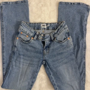 Ljusblå jeans med broderade bakfickor 157 - Ljusblå jeans från 157 med snygga broderade detaljer på bakfickorna. Klassisk femficksmodell med dubbla knappar i midjan och utsvängda i benen. Jeansen har en cool tvätt och kontrastsömmar som ger extra stilpoäng.(jeansen är lågmidjade)