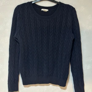 Mörkblå stickad tröja - Mörkblå stickad tröja från H&M med klassiskt flätmönster. Tröjan har rund halsringning och långa ärmar, perfekt för kyligare dagar. Enkel och stilren design som passar till det mesta.