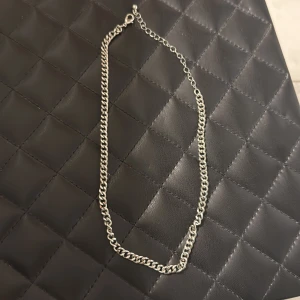 Kedjehalsband i silverfärg - Stilrent halsband med grov kedja i silverfärg. Justerbar längd med karbinlås, perfekt för att ge en edgy touch till din outfit. Passar både till lager-på-lager och som statement piece. INTE ÄKTA SILVER, köparen står för frakt :)