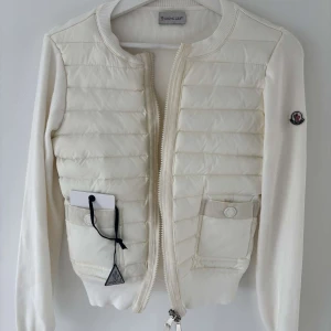 Vit quiltad cardigan jacka Moncler - Supersnygg vit cardigan jacka från Moncler med quiltad front och två fickor. Jackan har ribbade muddar, dragkedja och Moncler-logga på ärmen. Storlek S. Skriv vid intresse eller frågor
