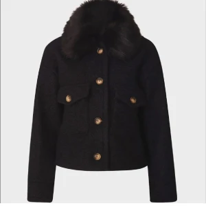 Svart teddyjacka med fuskpäls-krage - Säljer en svart teddyjacka med stor fuskpäls-krage och snygga knappar. Jackan täcker ner till magens slut och har två fickor med lock på bröstet. Perfekt för dig som vill ha en trendig och mysig look i höst och vinter. Jag vet inte vilken storlek det är men passar xs-s