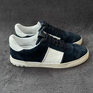 Valentino Rockstud sneakers mocka svart/vit - Snygga Valentino Rockstud sneakers i svart mocka med vita skinnpaneler och coola nitar på hälen. Klassisk låg modell med svarta snören och vit sula. Perfekta för dig som vill sticka ut med en lyxig och edgy stil.