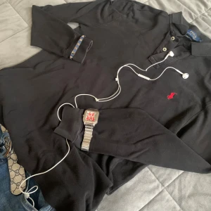Svart pikétröja från Polo Ralph Lauren - Svart pikétröja från Polo Ralph Lauren i slim fit. Tröjan är i okej skick. En av lapparna i nacken har lossnat lite samt så är den lite sydd i på höger axel (se bilder). Inget som man tänker på eller syns. Tröjan är storlek M (fits S). Den är för liten för mig och jag har medium i vanliga fall. Hör av er vid funderingar 😊