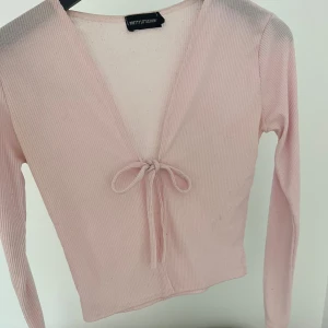 Ljusrosa ribbad topp PrettyLittleThing - Säljer en super söt och skön ”knyt-kofta” från pretty little thing i storlek 34/S. Säljer då jag tyvärr växt ur den. Inga defekter. Perfekt inför höst!  Nypris ≈ 300 säljer för 100 kr 