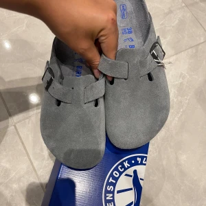  Birkenstock Boston - Säljer ett par grå Birkenstock Boston sandaler i mocka med justerbart spänne i metall. Storlek 38, soft touch. Helt nya med prislappen