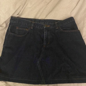 Mörkblå jeanskjol i storlek 40 - Superfin mörkblå jeanskjol med snygga bakfickor!! osäker på märket då jag köpt den secondhand! Helt oanvänd