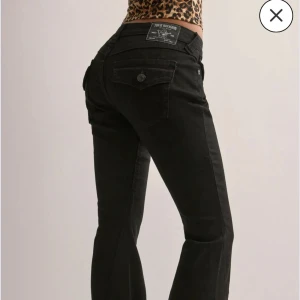 Svarta bootcut jeans från True Religion - Svarta jeans från True Religion i modellen JOEY LOW RISE FLARE. med klassisk femficksdesign och tydlig logga på bakfickan. Byxorna har bootcut-modell med utsvängda ben och normal midja. Tillverkade i stretchig denim för en bekväm passform och snygg siluett. 