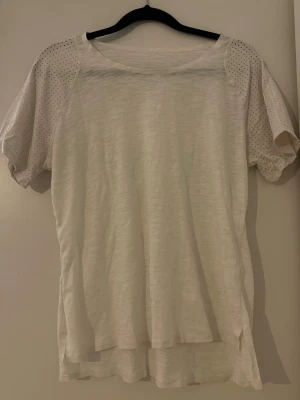 Vit tränings t-shirt - Säljer en vit tränings t-shirt med korta ärmar i mesh-tyg med små prickar. 