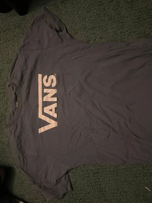 Svart Vans t-shirt med logga - Svart t-shirt från Vans med stor vit logga tryckt på bröstet. Klassisk passform och rund halsringning. Perfekt för dig som gillar streetwear och vill ha en enkel men snygg look.