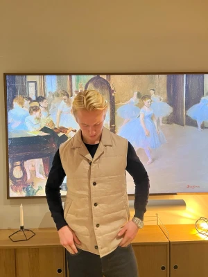 Beige dunväst från these glory days - Stilren beige dunväst med klassisk krage och knäppning framtill. Västen har en quiltad design och raka linjer, perfekt att slänga över en hoodie eller långärmad tröja. Passar dig som gillar en clean och enkel look. Sjukt snygg väst! Knappast andvänd och köpt i butik, kvittot är tyvvär bort slarvat men 100% äkta. Säljer pga ingen andvändning. Pris ej hugget i sten hör av dig vid minsta fundering!! Mvh Leo💪🏻✌🏻