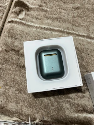 TWS Earbuds J18 trådlösa hörlurar - Snygga TWS Earbuds J18 i metallic grön färg med laddningsetui. Hörlurarna är trådlösa och har en stilren design med rundade kanter. Perfekta för musik, samtal och gaming. Kommer i originalförpackning.