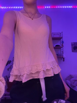 Ljusrosa linnetopp med volang - Säljer ett ljusrosa linne med rund halsringning och dubbla volangkanter nertill, varav den översta har spetsdetaljer. Perfekt för en söt och avslappnad stil. Materialet känns mjukt och lätt. Tvättar såklart innan jag skickar. Priset kan diskuteras. Använd ett fåtal gånger. Storlek 146-152.