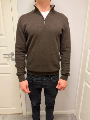 Brun halvzip-tröja John Henric - Snygg brun stickad tröja från John Henric med halv dragkedja och hög krage. Tröjan har ribbade muddar vid ärmslut och nederkant samt en mjuk, skön känsla. Perfekt för lager-på-lager och stilrena outfits. Ts Ai 