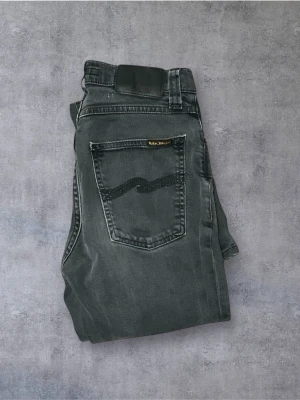  Nudie Jeans - Snygga svarta jeans från Nudie Jeans med klassisk femficksdesign och diskret logga på bakfickan. Jeansen har en rak passform och är tillverkade i mjukt bomullstyg med en lätt tvättad look. Perfekta för en stilren vardagsoutfit.