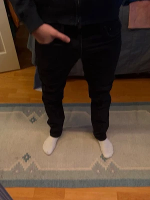 Svarta slim jeans 501 från Levi’s - Säljer ett par svarta jeans med rak passform och klassisk femficksdesign från Levi’s. Jeansen har normal midja och är tillverkade i ett mjukt bomullsmaterial med lite stretch för extra komfort. Perfekta till sneakers eller boots.