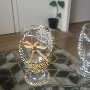 •	Dekorativa dryckesglas  - Två olika pärlband, ett i guld med satinrosett och ett i silver med glittrande stenar. Perfekta som kreativa smyckesdetaljer eller för att pynta accessoarer. Materialet är plast och textil, färgerna är guld och silver med inslag av bling och rosett.