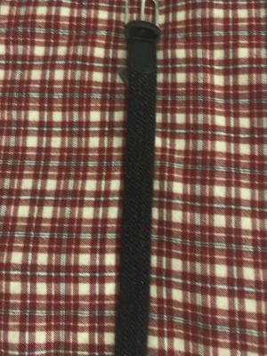 Svart flätat bälte med metallspänne - Snyggt svart flätat bälte med silverfärgat metallspänne och detaljer i konstläder. Bältet har en stilren look och passar perfekt till jeans eller byxor för en trendig touch.