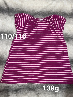 Lila och vit randig klänning - Söt klänning i lila med vita ränder och korta ärmar. Klänningen har en avslappnad passform och är perfekt för varma dagar. 🌸 Fint använt skick. Storlek 110/116