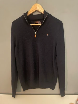 Mörkblå halvzip-tröja från Morris - Snygg mörkblå stickad tröja från Morris med halv dragkedja och liten broderad logga på bröstet. Tröjan har hög krage, långa ärmar och ribbade muddar. Perfekt för lager-på-lager och stilren look. Nypris 1200. Mitt pris 549!