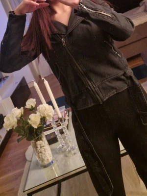 Svart jacka med dragkedja - Snygg svart jacka med klassisk bikerstil och dragkedjor på ärmarna. Jackan har en markerad krage och fickor framtill. Perfekt för dig som vill ha en edgy look till vardags.