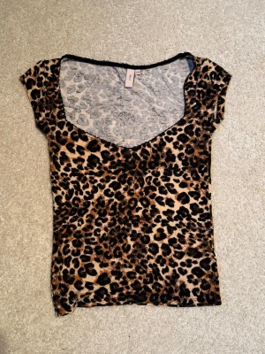 Leopardmönstrad tight topp - Populär snygg tight topp med leopardmönster och djup v-ringning. Kortärmad modell i stretchigt material som sitter slimmat mot kroppen. 