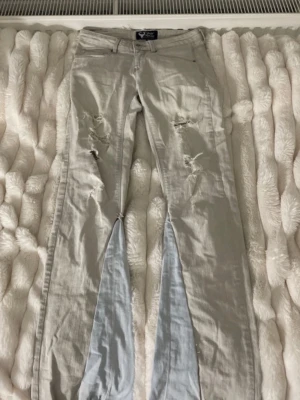 Ljusgrå ripped bootcut jeans - Snygga ljusgrå jeans med bootcut-modell och slitna detaljer på låren och knäna. Jeansen har klassisk femficksdesign och är tillverkade i ett mjukt bomullsmaterial. De är låga och sko snöret syns inte när man har på sig byxorna, om ni vill se på så skriv till mig!💕