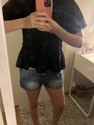 (Kolla beskrivning för storlek)Svart volang t-shirt med resår Veramoda - Tröjan köptes i xl men har krympt i tvätten så den är runt storlek M skulle jag säga. Säljer en svart t-shirt med volangkant nedtill och resår i midjan. T-shirten har korta ärmar och en loose passform. 