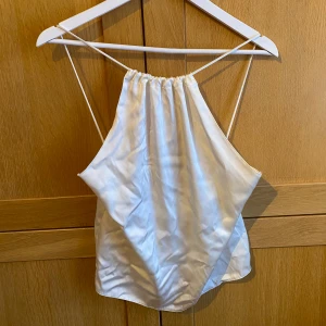 Vit satin halterneck topp - Säljer ett satinlinne med tunna axelband och halterneck-modell från Zara.  Öppet i ryggen. Helt ny aldrig använd🤍