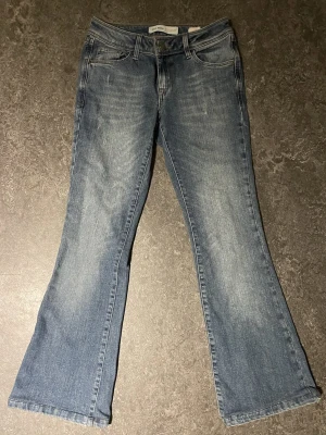 Blå flare jeans från Mos Mosh - Snygga blå jeans från Mos Mosh med flare-ben och klassisk femficksdesign. Jeansen har en lätt tvättad look och normal passform. Storlek 26 vilket motsvarar storlek 34. Midjan tvärs över är 33cm! Korta för mig därför jag säljer.
