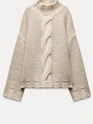 Beige stickad tröja med fläta - Mysig beige stickad tröja med hög hals och en bred fläta framtill. Tröjan har ribbade kanter och en lös, avslappnad passform. Perfekt för kalla dagar och enkel att styla till olika outfits.